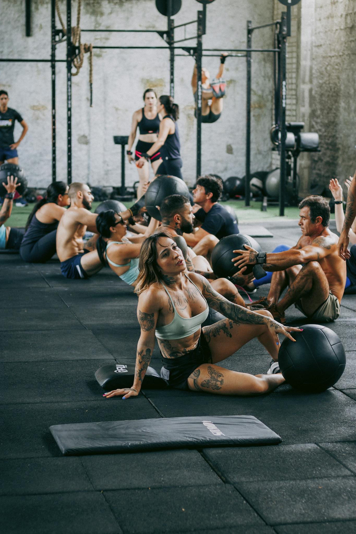 A diverse group of adults engaging in an intense fitness class using medicine balls indoors.